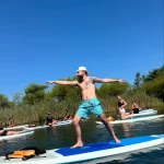 man on paddleboard doing yoga